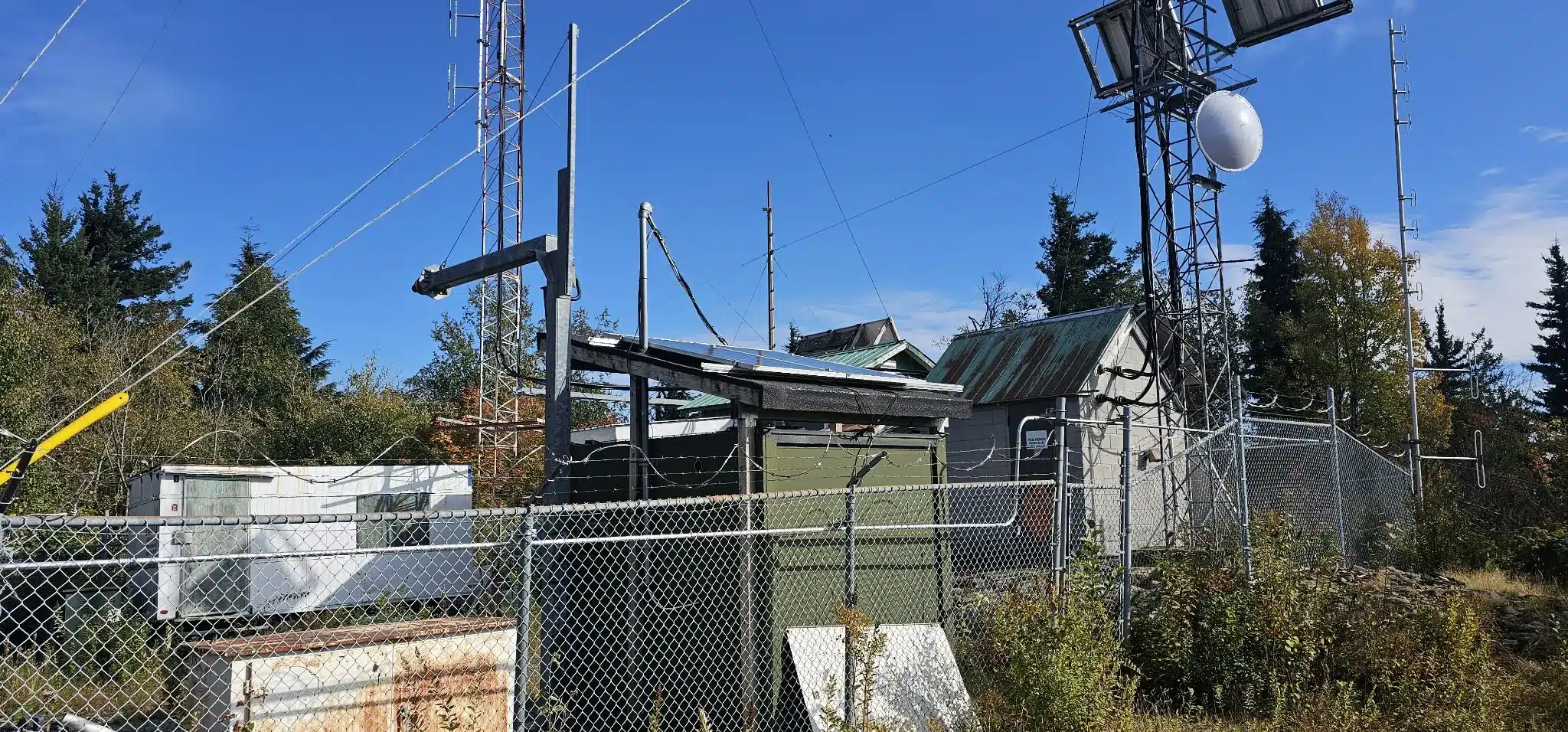 Communication towers, fenced equipment and solar panels near the summit of Taggart Peak in Abbotsford