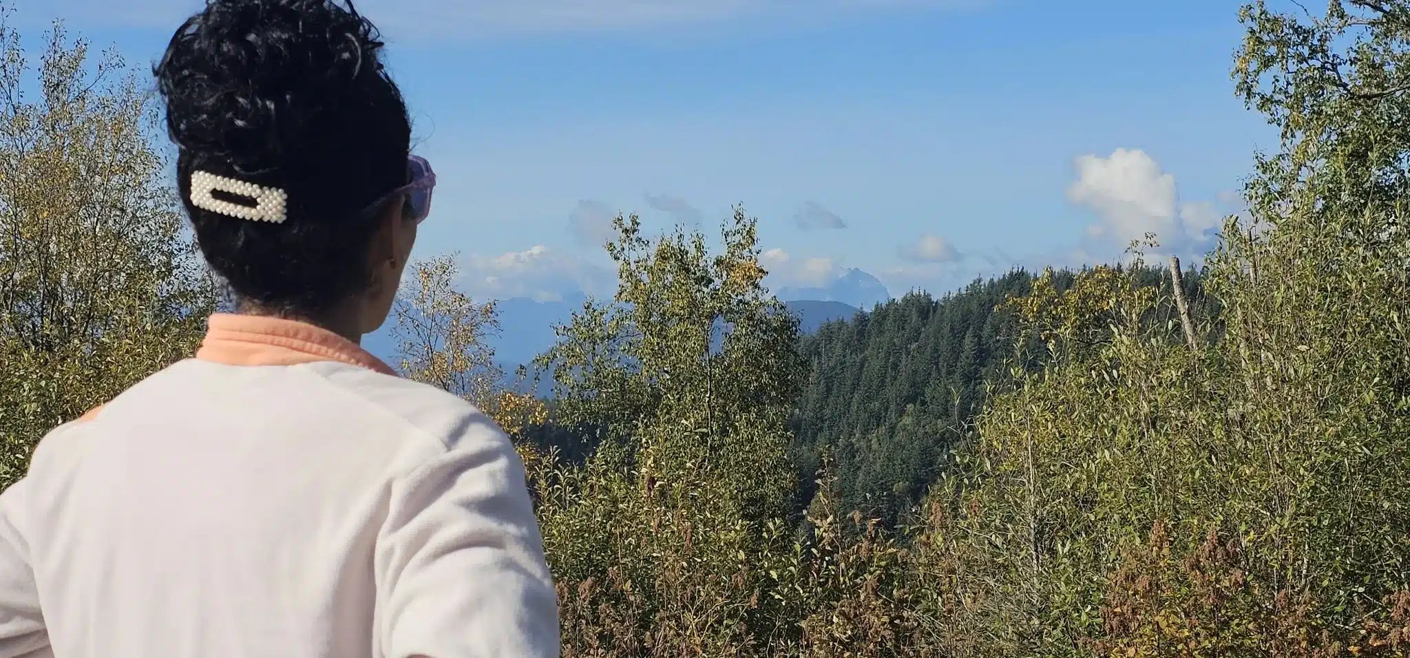 Hiker at the forested summit of Taggart Peak in Abbotsford with distant Coast Mountains visible